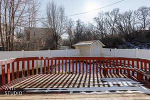 Wooden deck featuring a fenced backyard and a shed