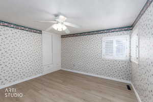 Spare room featuring light wood-style floors and wallpapered walls