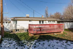 Rear view of house featuring a wooden deck, a chimney, and a gate