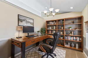 Home office with a chandelier and light colored carpet