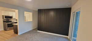 Kitchen with appliances with stainless steel finishes, light countertops, light carpet, and white cabinetry