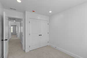 Unfurnished bedroom with light carpet, a closet, and recessed lighting