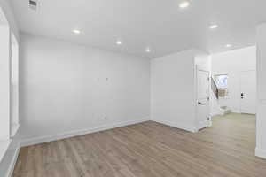 Unfurnished room featuring light wood finished floors, recessed lighting, and stairway