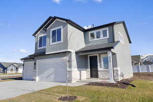 View of front facade featuring a garage, driveway, stucco siding, stone siding, and a porch