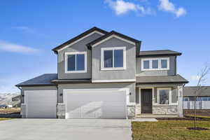 View of front of home with stucco siding, stone siding, driveway, a garage, and a shingled roof