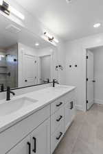 Bathroom with double vanity, a shower stall, light tile patterned flooring, and recessed lighting