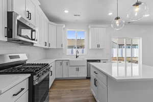 Kitchen featuring appliances with stainless steel finishes, white cabinetry, backsplash, and recessed lighting
