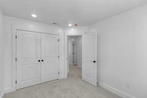 Unfurnished bedroom featuring light colored carpet, a closet, and recessed lighting