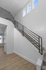 Stairs featuring a towering ceiling and wood finished floors