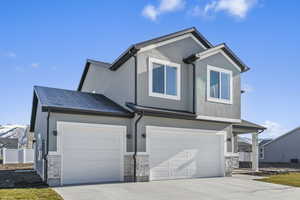 View of front of house featuring stone siding, stucco siding, concrete driveway, and an attached garage