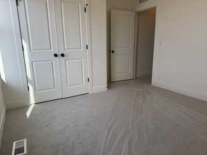 Unfurnished bedroom with light colored carpet and a closet