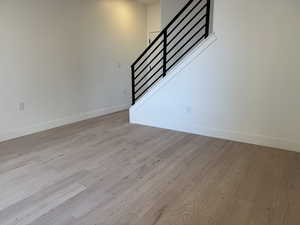 Unfurnished living room featuring light wood-type flooring and stairway