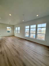 Unfurnished living room with light wood finished floors, recessed lighting, and a chandelier