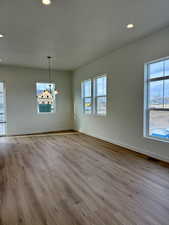 Unfurnished dining area featuring light wood-type flooring, recessed lighting, healthy amount of natural light, and a chandelier