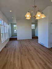 Unfurnished dining area with recessed lighting, healthy amount of natural light, wood finished floors, and a chandelier