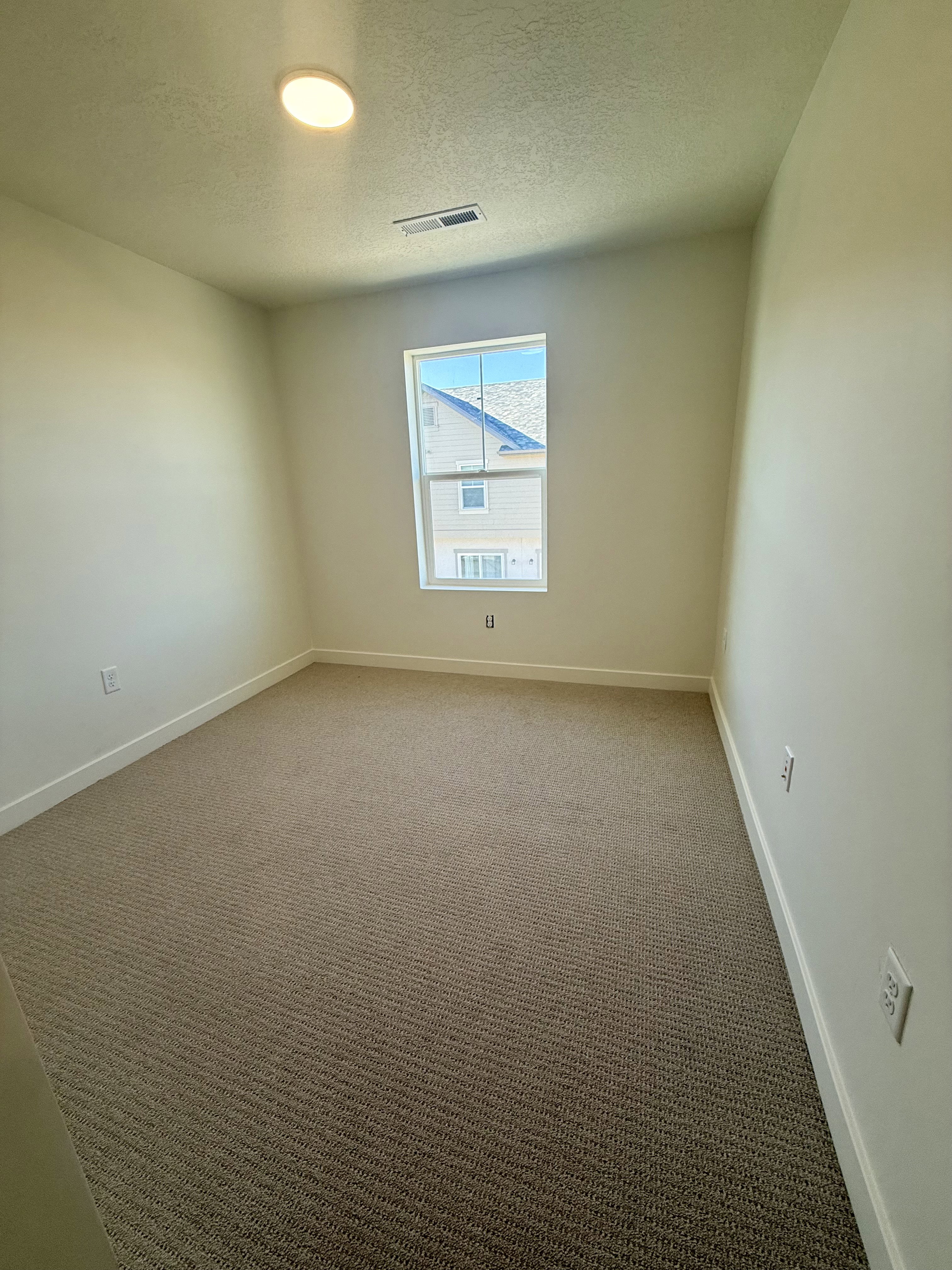 Carpeted spare room with a textured ceiling and baseboards