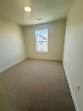 Carpeted spare room with a textured ceiling and baseboards