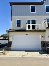 Traditional-style home with a garage, board and batten siding, a balcony, and concrete driveway