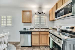 Kitchen with stainless steel appliances, dark countertops, and plenty of natural light