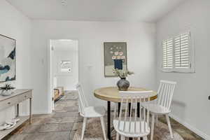 Dining space featuring stone tile flooring and baseboards