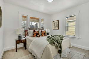 Bedroom featuring light carpet and multiple windows