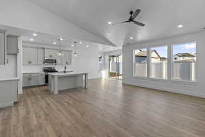 Kitchen featuring open floor plan, a kitchen breakfast bar, an island with sink, hanging light fixtures, and stainless steel appliances
