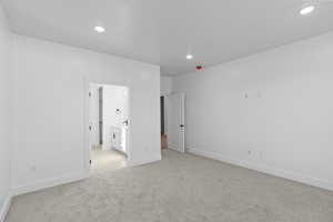 Unfurnished bedroom with light colored carpet, ensuite bathroom, and recessed lighting