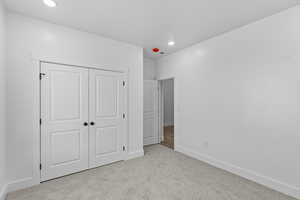 Unfurnished bedroom featuring light carpet, a closet, and recessed lighting