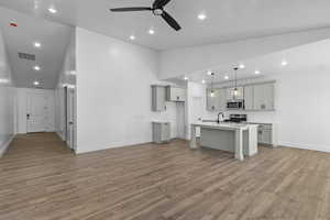 Kitchen with vaulted ceiling, a breakfast bar, a center island with sink, recessed lighting, and stainless steel appliances
