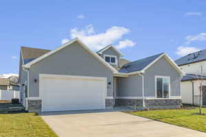 View of front facade featuring stone siding, a front lawn, and stucco siding