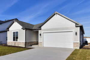 Craftsman-style house featuring stone siding, concrete driveway, a garage, a front yard, and a shingled roof