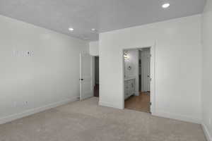 Unfurnished bedroom featuring light carpet, connected bathroom, and recessed lighting