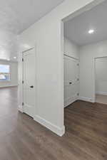 Hall with dark wood finished floors, recessed lighting, and a textured ceiling