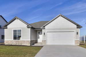 Craftsman-style home with stone siding, concrete driveway, a garage, a front lawn, and roof with shingles
