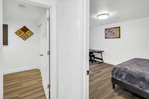 Bedroom featuring light wood finished floors, a textured ceiling, and an office area