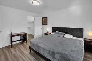 Bedroom with wood finished floors, a walk in closet, and a textured ceiling