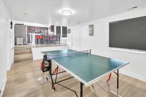 Recreation room featuring a textured ceiling and light wood finished floors
