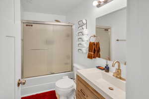 Bathroom with vanity and combined bath / shower with glass door