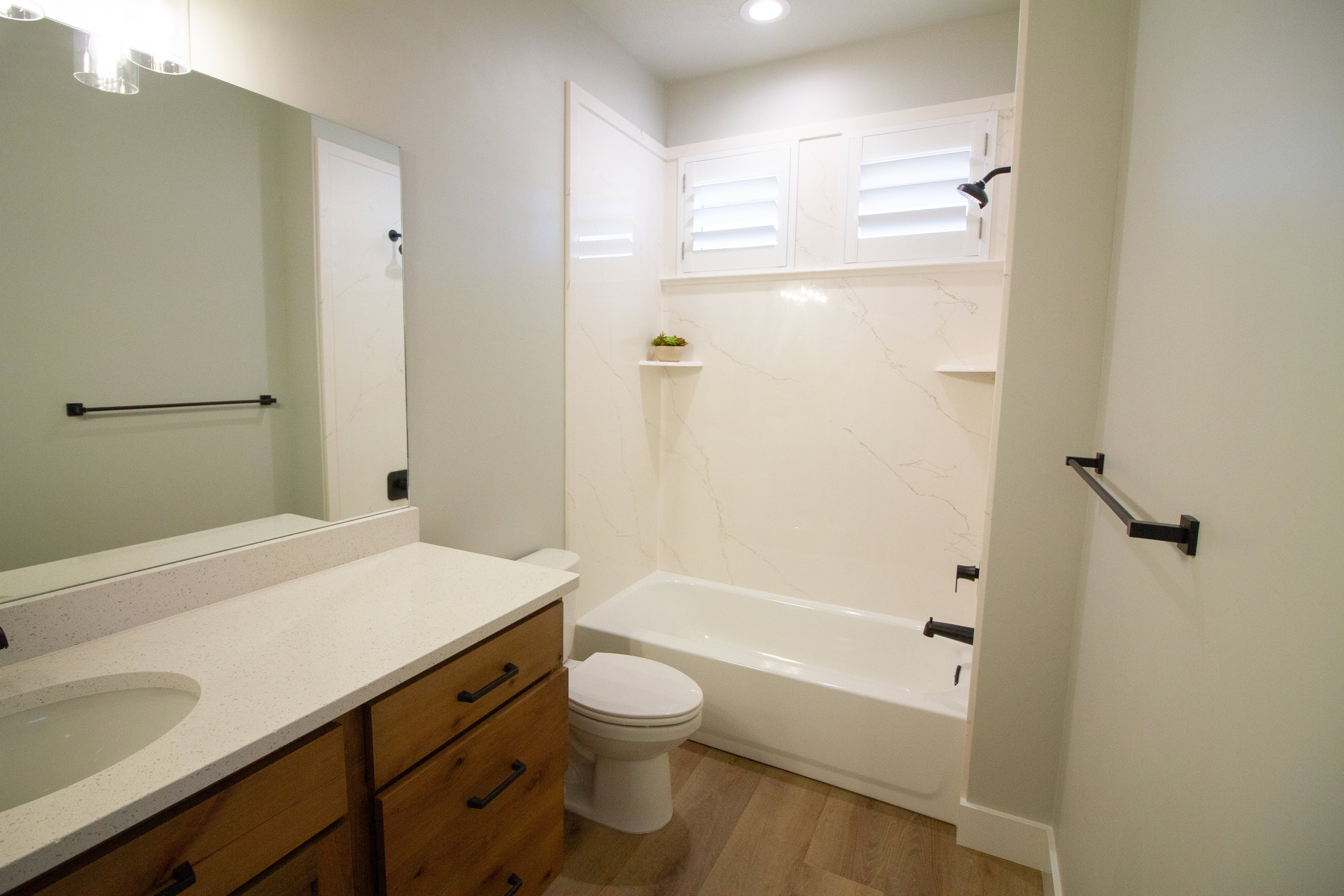 Full bath with vanity, a combined bath / shower with marble appearance, and light wood finished floors