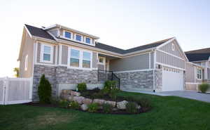 View of front facade featuring stone siding, concrete driveway, board and batten siding, and a garage