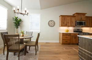 Dining room with light wood-style flooring, a chandelier, and lofted ceiling