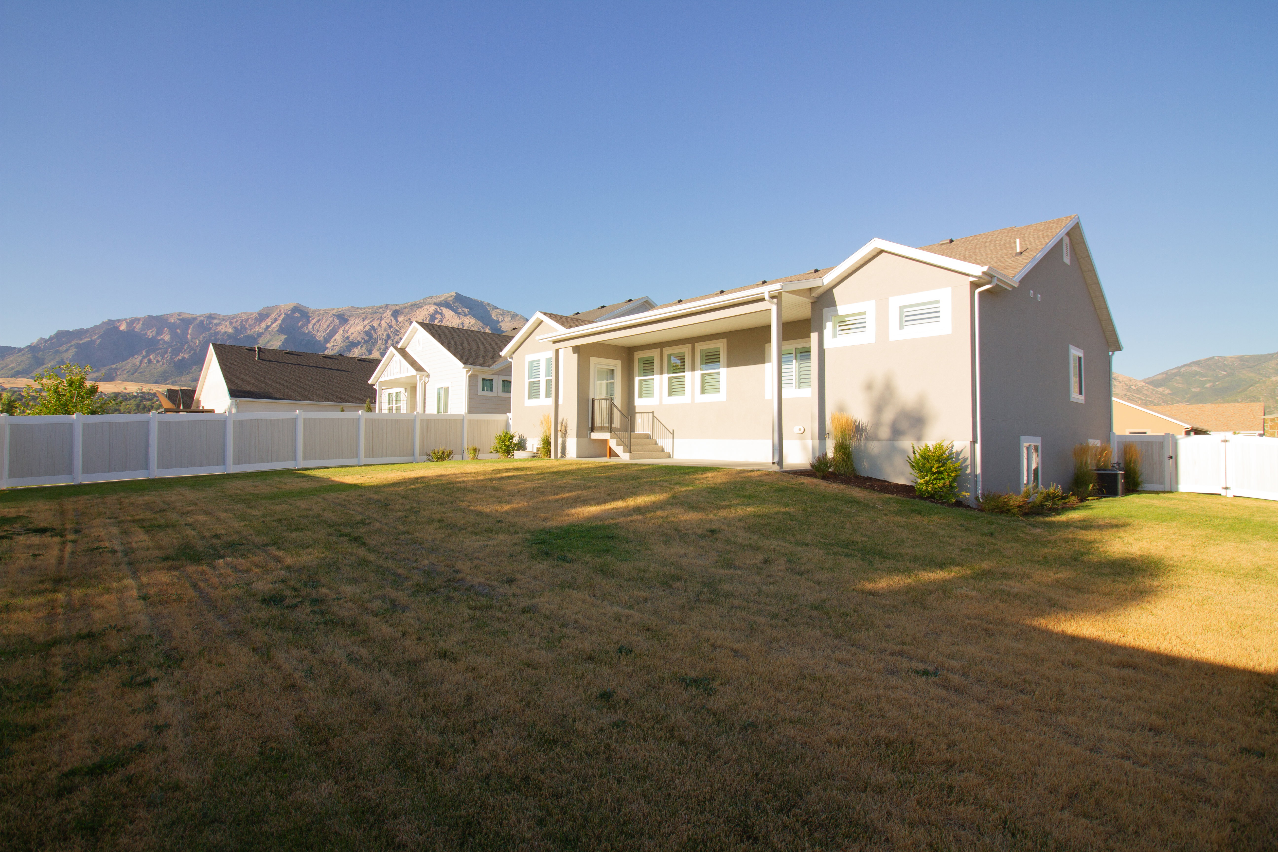 Rear view of house with a mountain view, a fenced backyard, and stucco siding