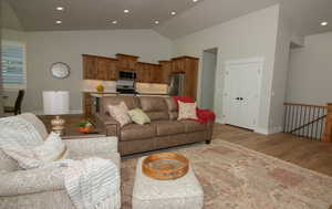Living room featuring light wood-type flooring, recessed lighting, and high vaulted ceiling