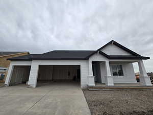 View of front of home featuring a garage, driveway, a porch, and roof with shingles