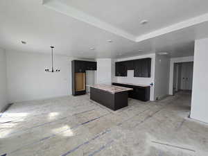 Kitchen with a kitchen island, hanging light fixtures, light countertops, and dark wood finish cabinets