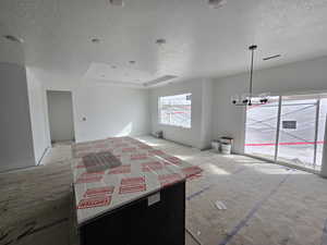 Interior space featuring a textured ceiling, a chandelier, and a tray ceiling
