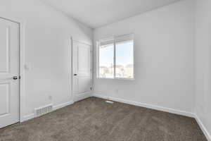 Unfurnished bedroom with dark carpet and baseboards