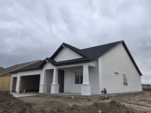 View of front of house with a porch, an attached garage, and roof with shingles