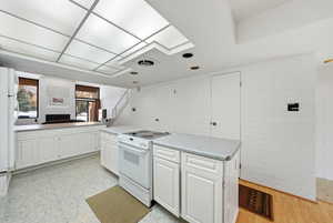 Kitchen featuring white cabinetry, white appliances, light countertops, and light floors
