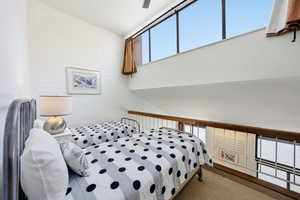 Bedroom with brick wall, ceiling fan, a high ceiling, and an accent wall